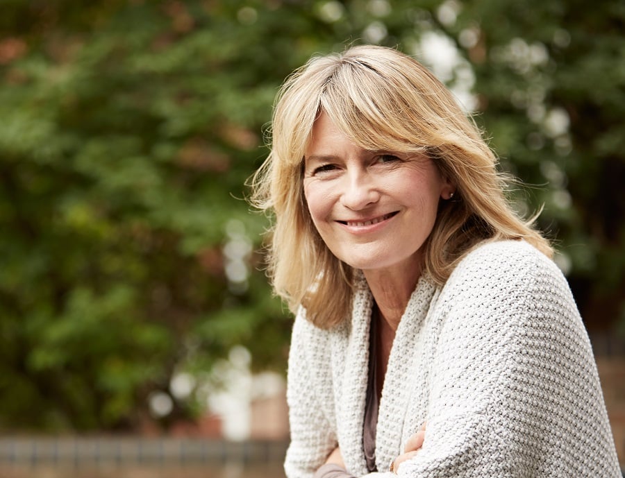 woman over 50 with layered blonde hair and round face