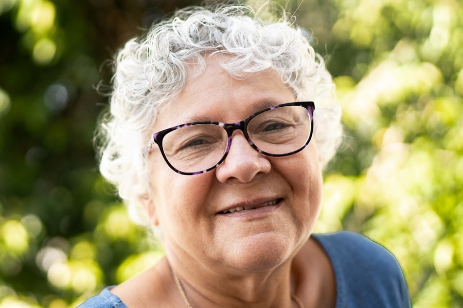 woman oveer 70 with short curly blonde hair and glasses