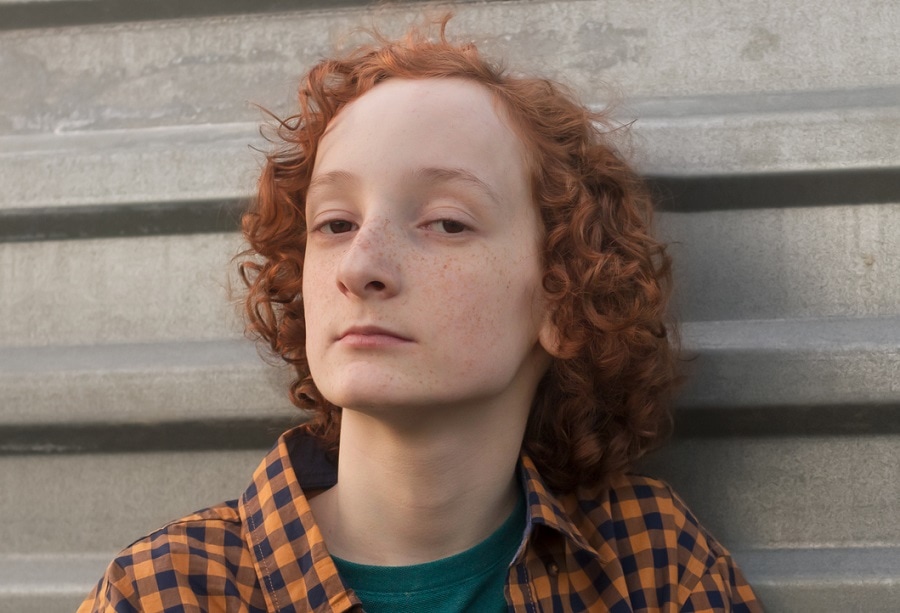 teen boy with long curly ginger hair